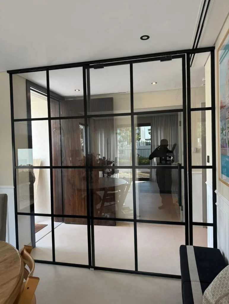 Black Crittall-style glass partition between living spaces — Renovation 786 Dubai
